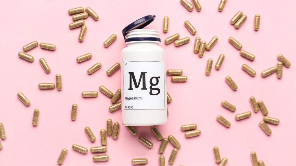 flacone di plastica con etichetta che indica il magnesio (Mg) con capsule intorno