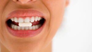 Donna che tiene compressa tra i denti bianchi