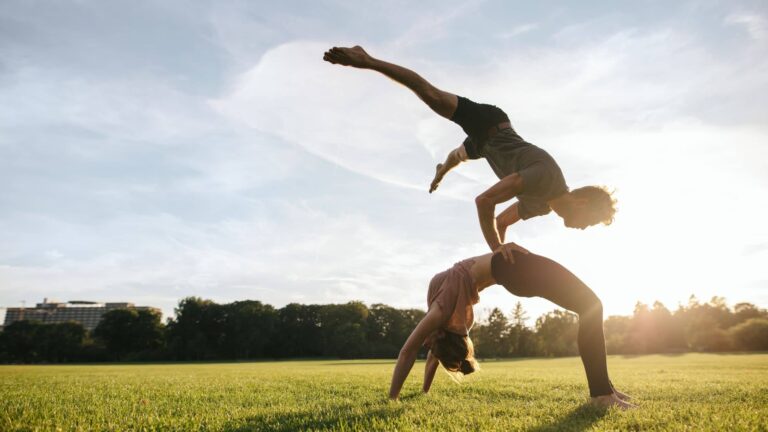 Una ragazza e un ragazzo mentre fanno una posizione difficile di yoga di coppia. La funzione mitondriale è assolutamente valida