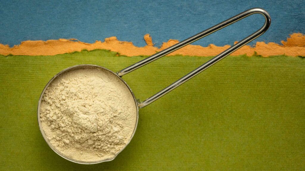 Pentolino con polvere di ashwagandha su sfondo verde e blu