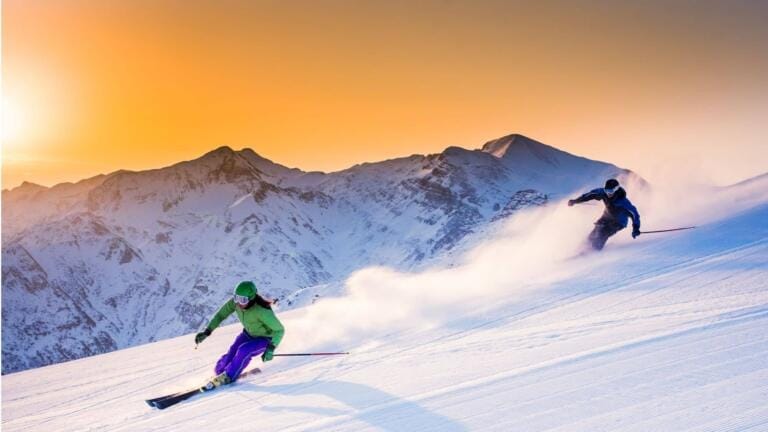 Due sciatori che sciano al tramonto come allenamento