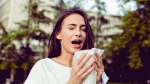 Ragazza in preda a rinite sta per starnutire quale sintomo della sindrome da allergia sistemica al nichel