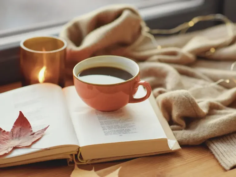 Un libro aperto e una tazza di caffè su un tavolo, simbolo di una pausa rilassante e disconnessa durante una giornata di digital detox