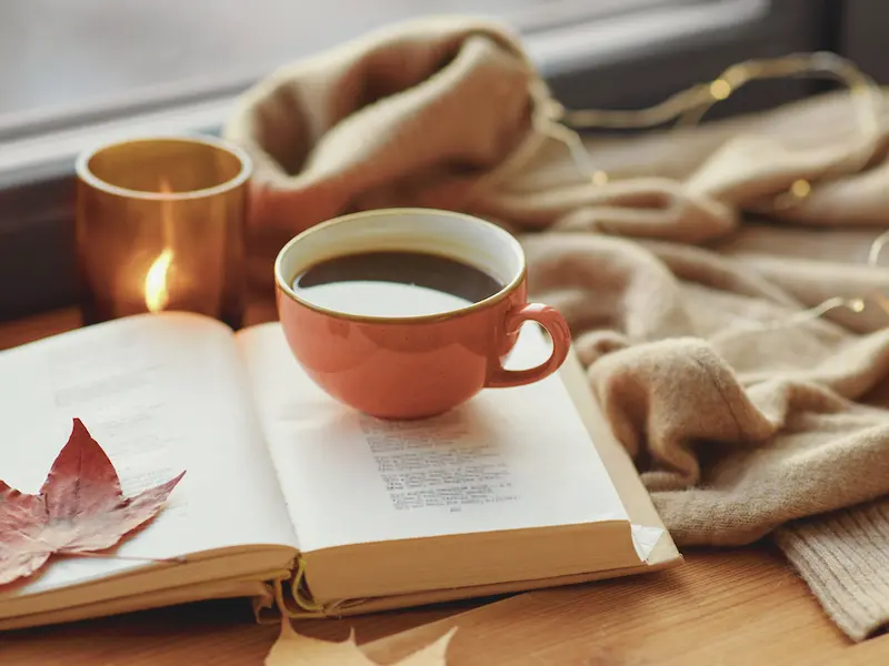 Un libro aperto e una tazza di caffè su un tavolo, simbolo di una pausa rilassante e disconnessa durante una giornata di digital detox