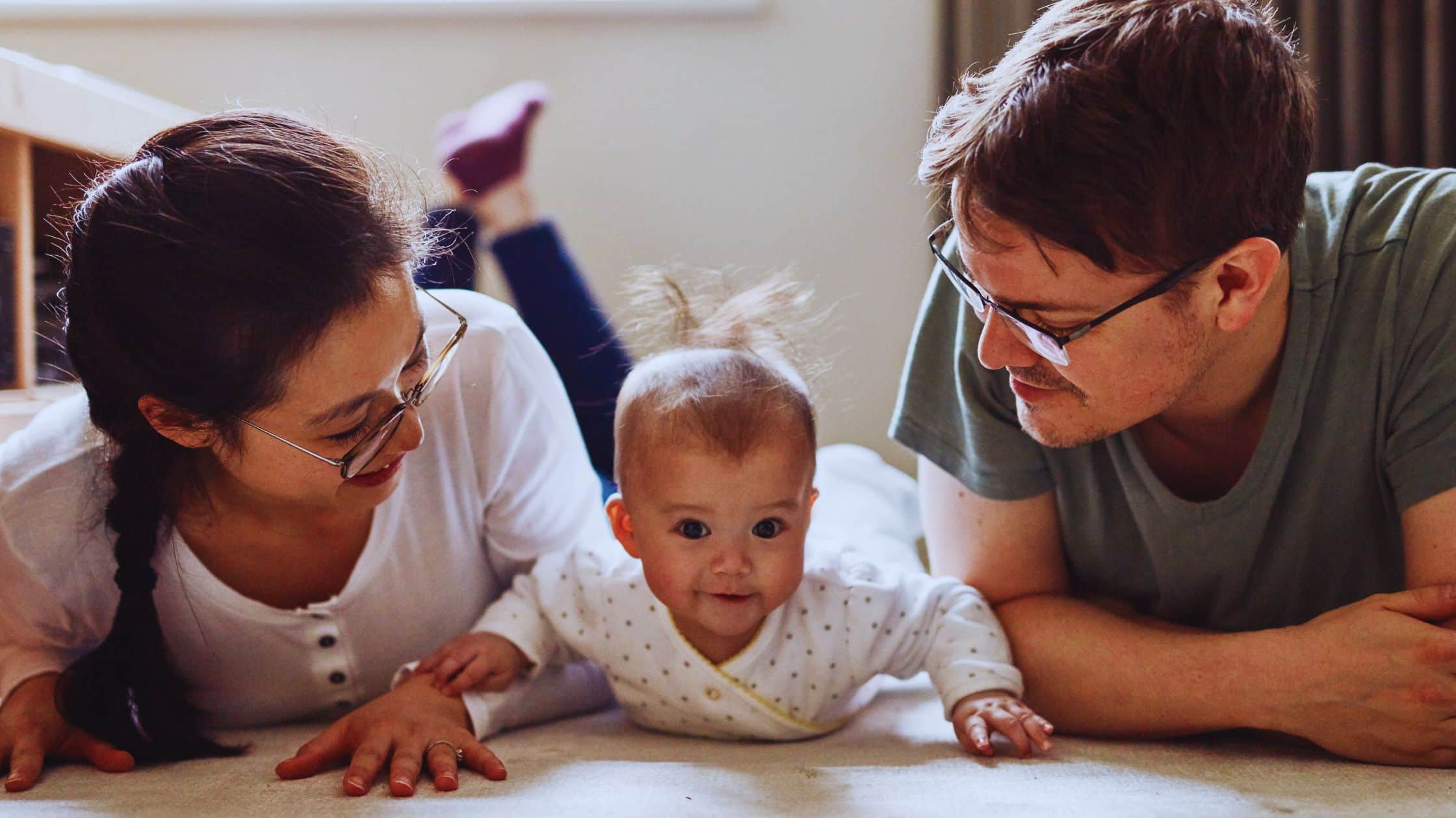 tummy time per adulti padre e madre sdraiati affianco al proprio neonato