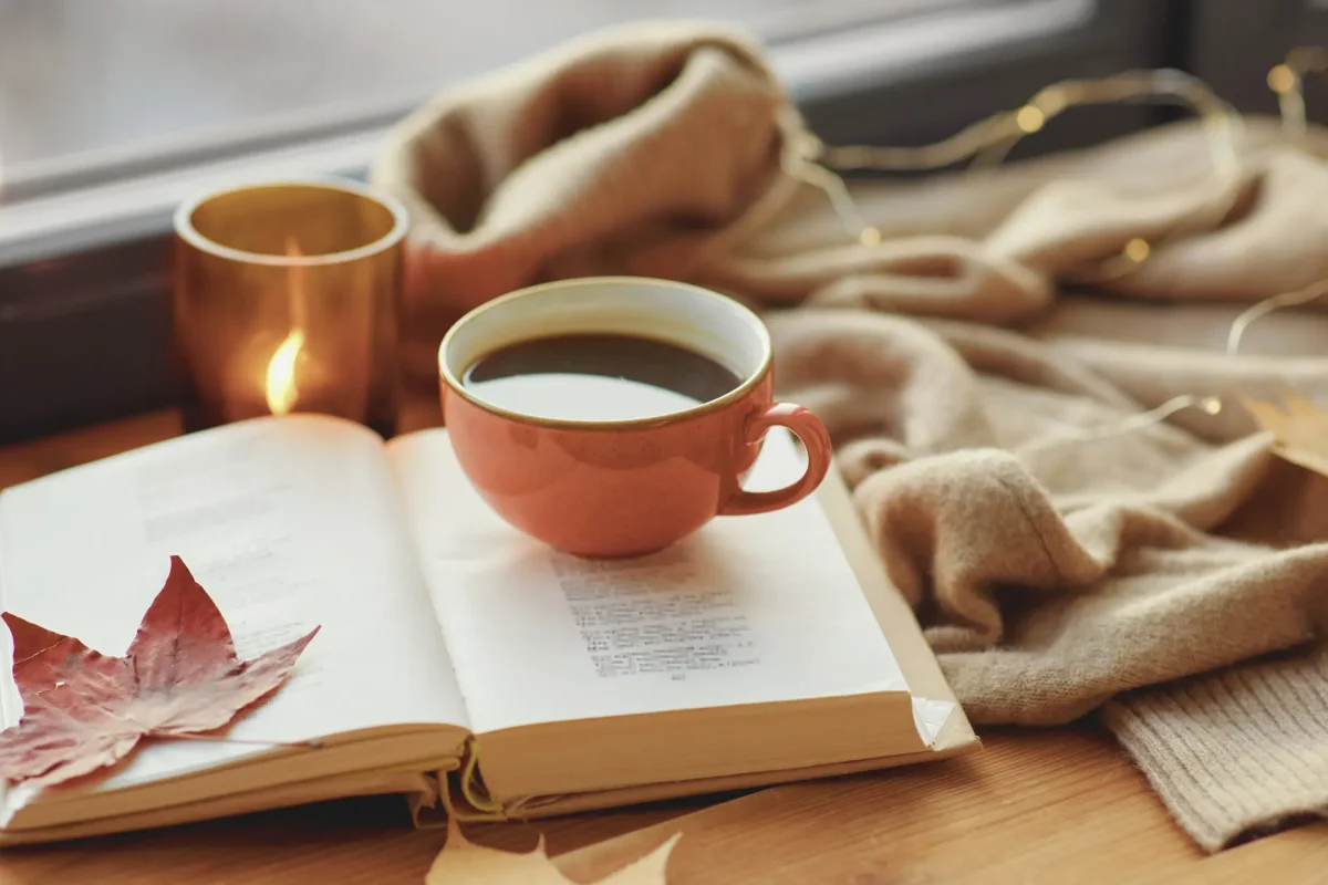 Un libro aperto e una tazza di caffè su un tavolo, simbolo di una pausa rilassante e disconnessa durante una giornata di digital detox